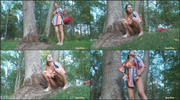 Playful brunette squats and pees near a tree